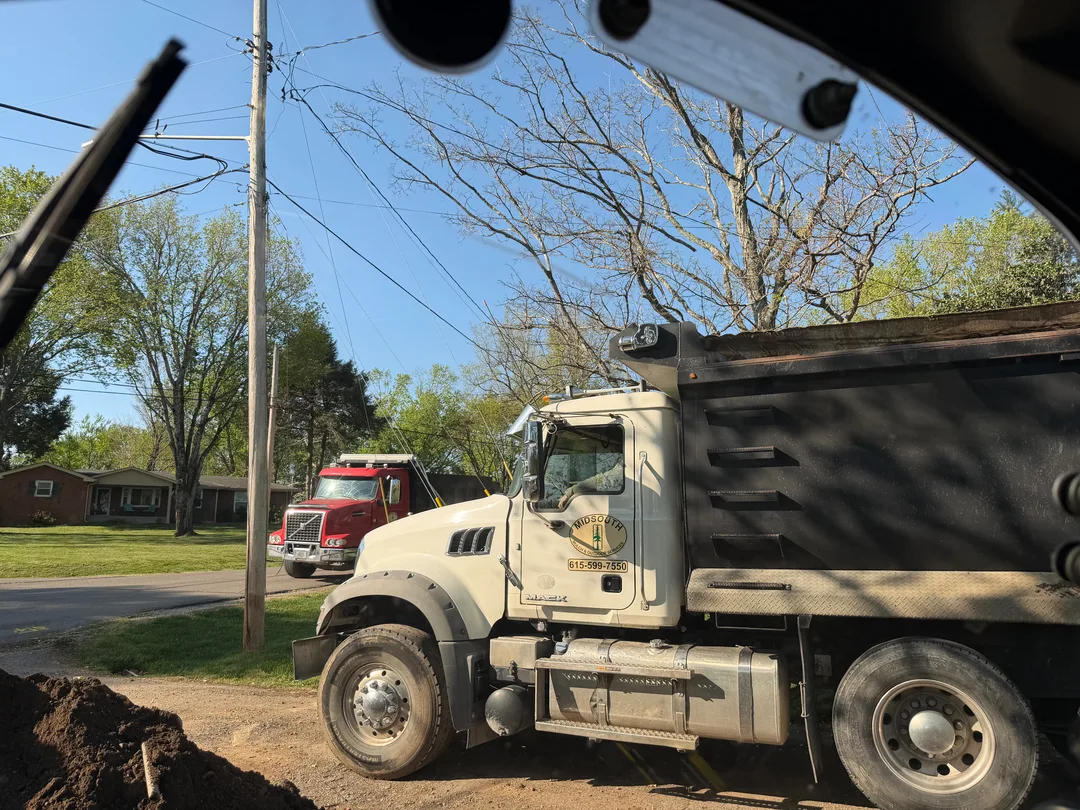 Dump truck working a residential street on a dirt run