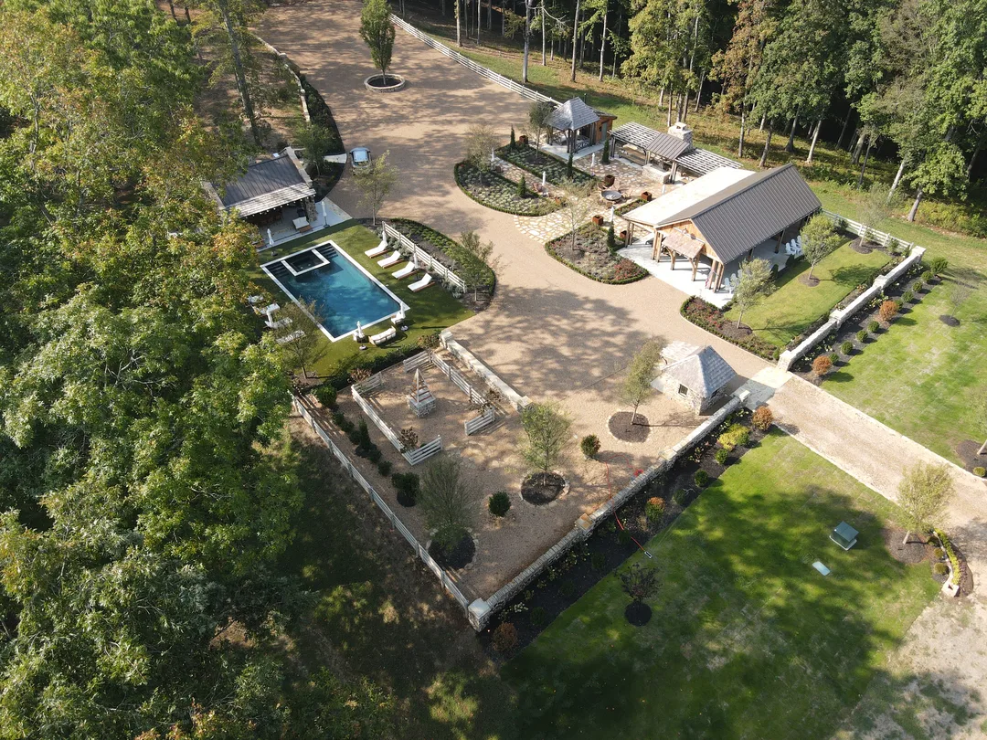 Aerial view of a maintained estate landscape with pool and grounds
