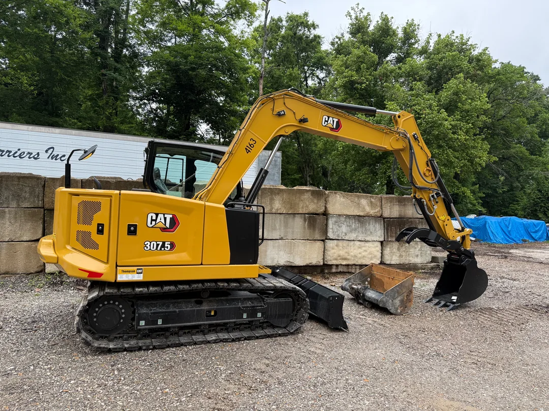 CAT excavator placing material at a block retaining wall