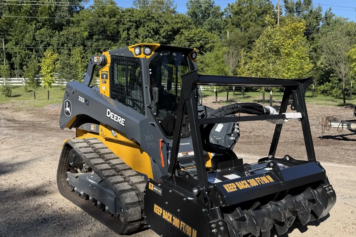 Compact track loader fitted with a forestry mulcher head for grinding brush in place